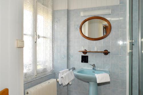 een blauwe badkamer met een wastafel en een spiegel bij Hotel de la gare in Cosne Cours sur Loire