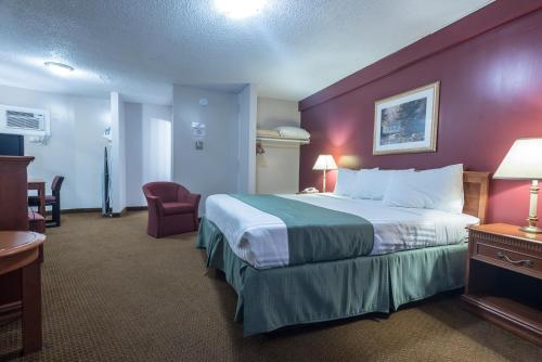 a hotel room with a large bed and a red wall at Port Augusta Inn in Comox