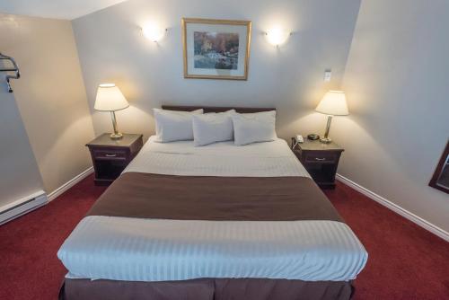 a large bed in a hotel room with two lamps at Port Augusta Inn in Comox