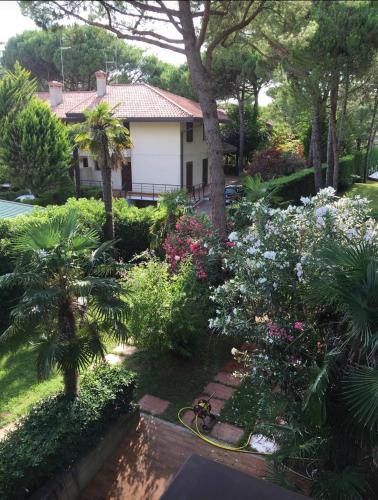 a garden with flowers and a house with a hose at Appartamento Soraya in Lignano Sabbiadoro