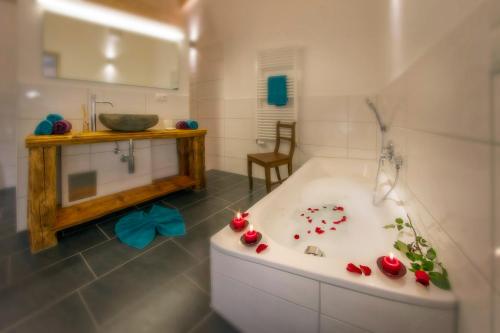 La salle de bains est pourvue d'une baignoire avec des roses rouges. dans l'établissement Landhaus Bergglühen, à Oberjoch