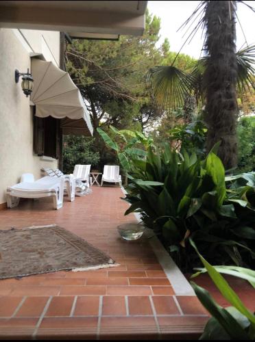 a patio with two white chairs and an umbrella at Appartamento Soraya in Lignano Sabbiadoro