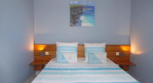 een slaapkamer met een bed met blauwe en witte kussens bij Appartement proche de la mer Ty Manganao in Saint-François