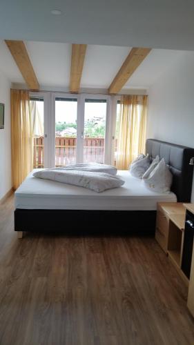 a large bed in a large room with windows at Pension Weinberg in Rifiano