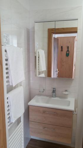 a bathroom with a sink and a mirror and towels at Pension Weinberg in Rifiano