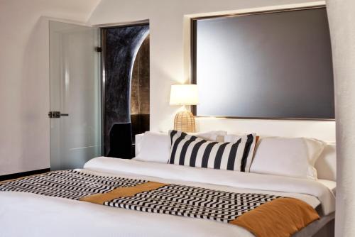 a hotel room with two beds and a mirror at San Antonio - Small Luxury Hotels of the World in Imerovigli