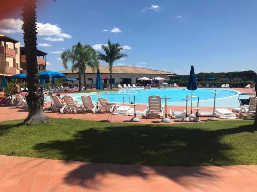 einen Pool mit Stühlen und Sonnenschirmen in einem Resort in der Unterkunft Blu Village 2 (MT) in Marina di Pisticci