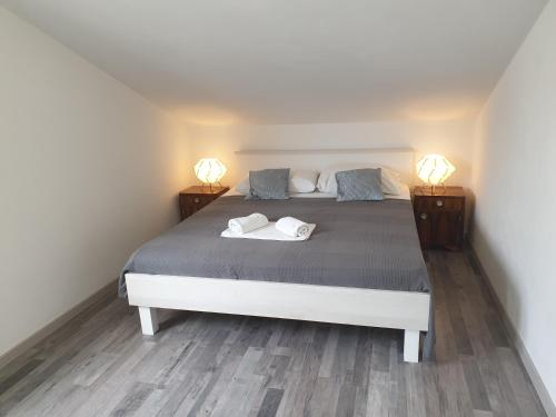 a bedroom with a bed with two lamps on it at Apartmani Dalmatinka in Metajna