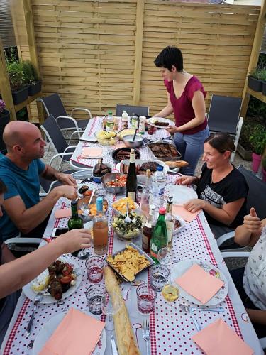 a group of people sitting around a long table with food at Au Nid de Tillé in Tillé