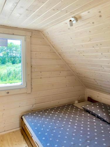 a bed in a wooden room with a window at Merinn in Rogowo