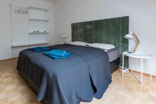Schlafzimmer mit einem Bett mit blauer Bettwäsche und einem Tisch in der Unterkunft Flataid Apartment Obere Bahnstraße - Grazer Messe in Graz