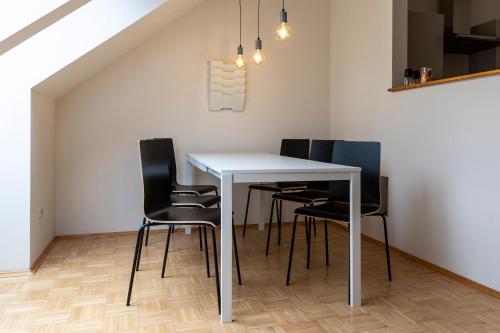 uma sala de jantar com uma mesa branca e cadeiras pretas em Flataid Apartment Obere Bahnstraße - Grazer Messe em Graz