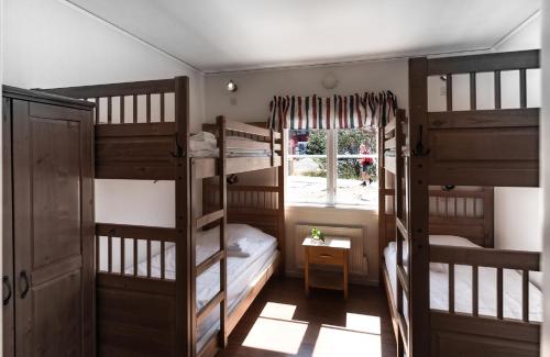 a room with three bunk beds and a window at Käringöns Vandrarhem in Käringön