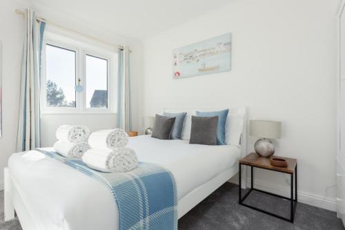 a white bedroom with a bed and a window at Fantasea in Poole