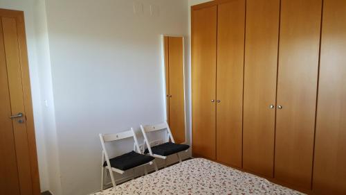 1 dormitorio con 2 sillas y armarios de madera en Apartamento en playa de Almenara con vistas a la Marjal en Almenara