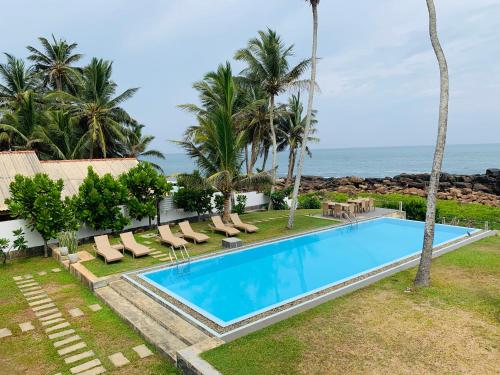 an image of a swimming pool with chairs and the ocean at Silverlane Beach House in Matara