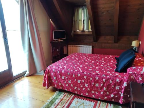 a bedroom with a bed with a red bedspread at Hotelet de Betlan in Betlán