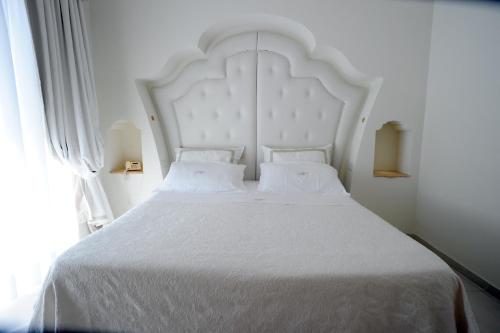 a white bed with a large white headboard and a window at Minori Palace in Minori
