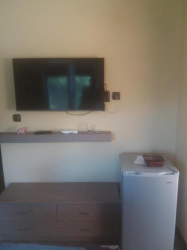 a television on the wall of a room with a refrigerator at Studio Lux in Pleven