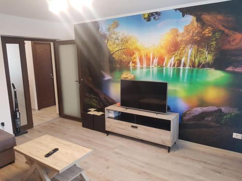 uma sala de estar com televisão e uma pintura na parede em Apartament Cosmin em Călimăneşti