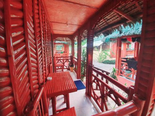 un balcón con una mesa roja y bancos. en Pareja Tourist Inn, en Isla de Malapascua