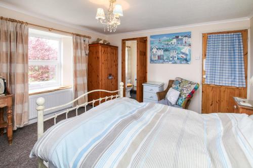 a bedroom with a bed and a chair in it at Vine Cottage in Penpillick