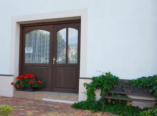 a wooden door on a building with flowers and a bench at Apartmán Nové Hrady in Nové Hrady
