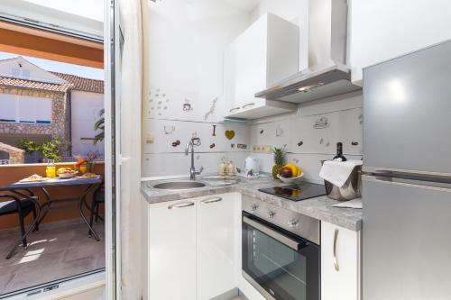a kitchen with white cabinets and a sink at Guest House Marinna in Vrboska