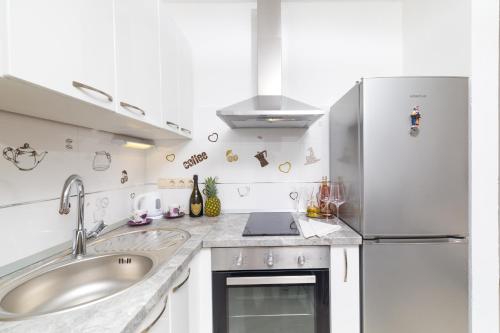 a white kitchen with a sink and a refrigerator at Guest House Marinna in Vrboska