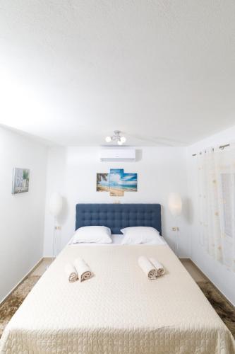 a white bedroom with a blue bed with two slippers at Guest House Marinna in Vrboska