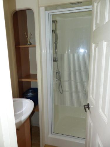 a glass shower in a bathroom with a sink at Domki nad Wartą in Wierzchlas