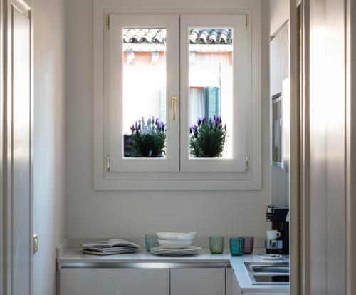 a kitchen with two windows with flowers in them at Residenza Ducato in Venice