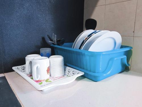 a blue plastic container with dishes and cups on a counter at Agus Hidden Homestay - Banjar Sweet Village-Ijen in Banyuwangi
