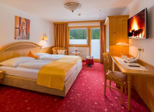 a hotel room with a bed and a desk at Hotel-Garni Jakober - B&B und Appartements in Tux