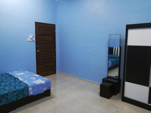 een blauwe kamer met een bed en een spiegel bij HOMESTAY DAMAI YUSMILA in Kuala Terengganu