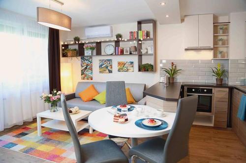 a kitchen and a living room with a table and chairs at Monarchia Apartman Sunny in Mosonmagyaróvár