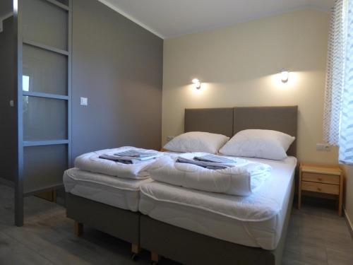 a bedroom with a bed with white sheets and pillows at Żubr Nad Zalewem in Łuka