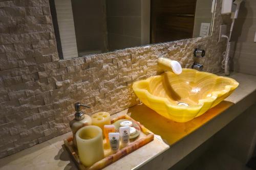 a bathroom with a yellow sink and toiletries on a counter at Hotel Villas Punta Blanca in Zihuatanejo