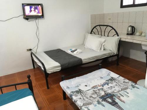 a room with a bed and a tv and a table at Budget Rooms in Silang Near Tagaytay in Silang