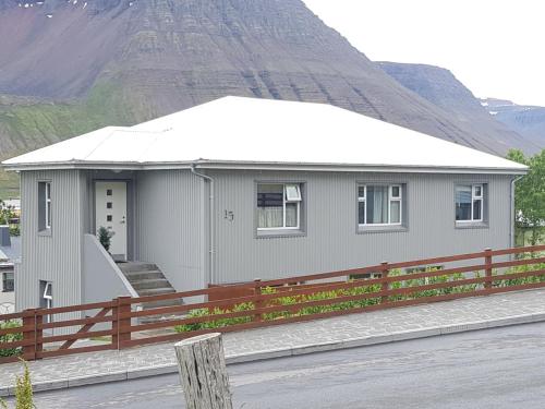 a small house with a mountain in the background at Sigurhæð - Apartment with all within your reach in Ísafjörður