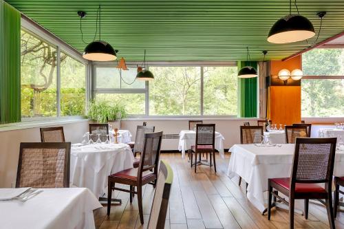 un ristorante con tavoli e sedie bianchi e finestre di Hotel Santoli a Porretta Terme