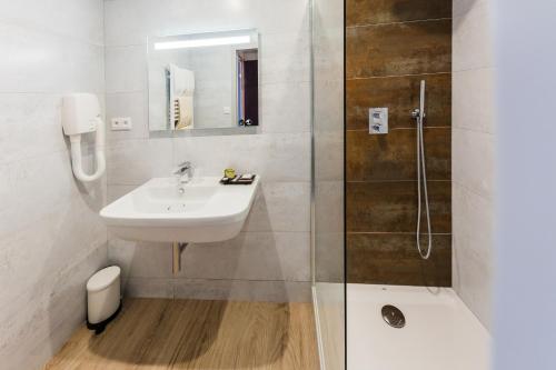 a white bathroom with a sink and a shower at Hotel Aigue Marine in Tréguier