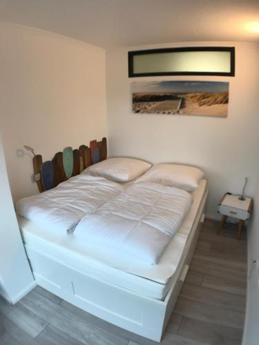 uma cama branca num quarto com uma fotografia na parede em Ferienwohnung Steffi Marina Wendtorf em Wendtorf