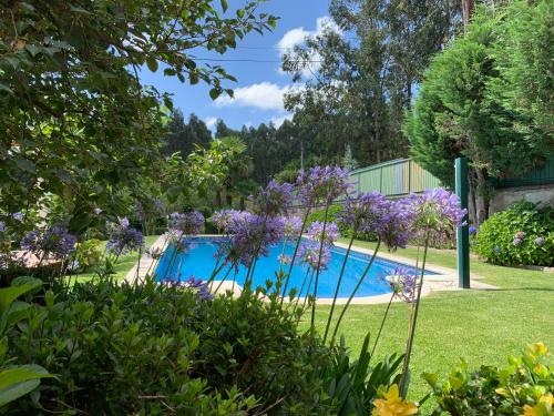 a swimming pool in a garden with purple flowers at Vila Aurora in Parada de Gatim
