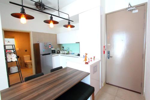a kitchen with a wooden table and a refrigerator at Afiniti Residensi Legoland Medini in Nusajaya