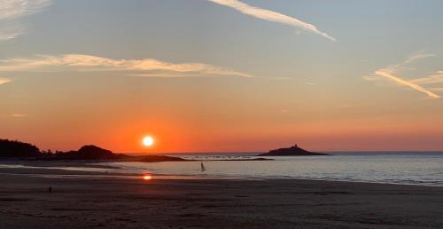a sunset on a beach with the sun setting at Datcha du Cap Fréhel in Plévenon