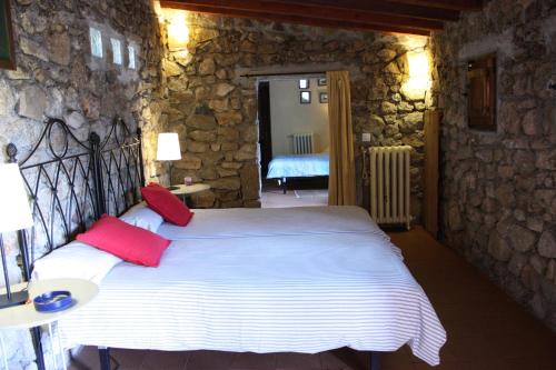 1 dormitorio con 1 cama blanca grande con almohadas rojas en La Quinta de los Enebrales, en El Hoyo de Pinares