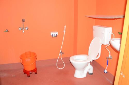an orange bathroom with a toilet and a sink at Kundanbazar Guest House in Bodh Gaya