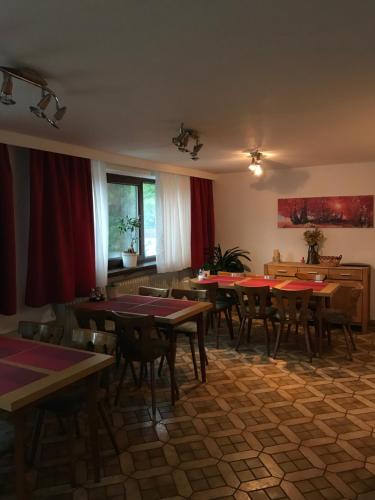 ein Esszimmer mit Tischen, Stühlen und roten Vorhängen in der Unterkunft Hotel Tannenhof in Bodenmais