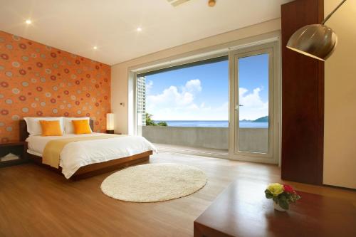 a bedroom with a bed and a large window at Tropical Dream Spa Resort in Geoje 